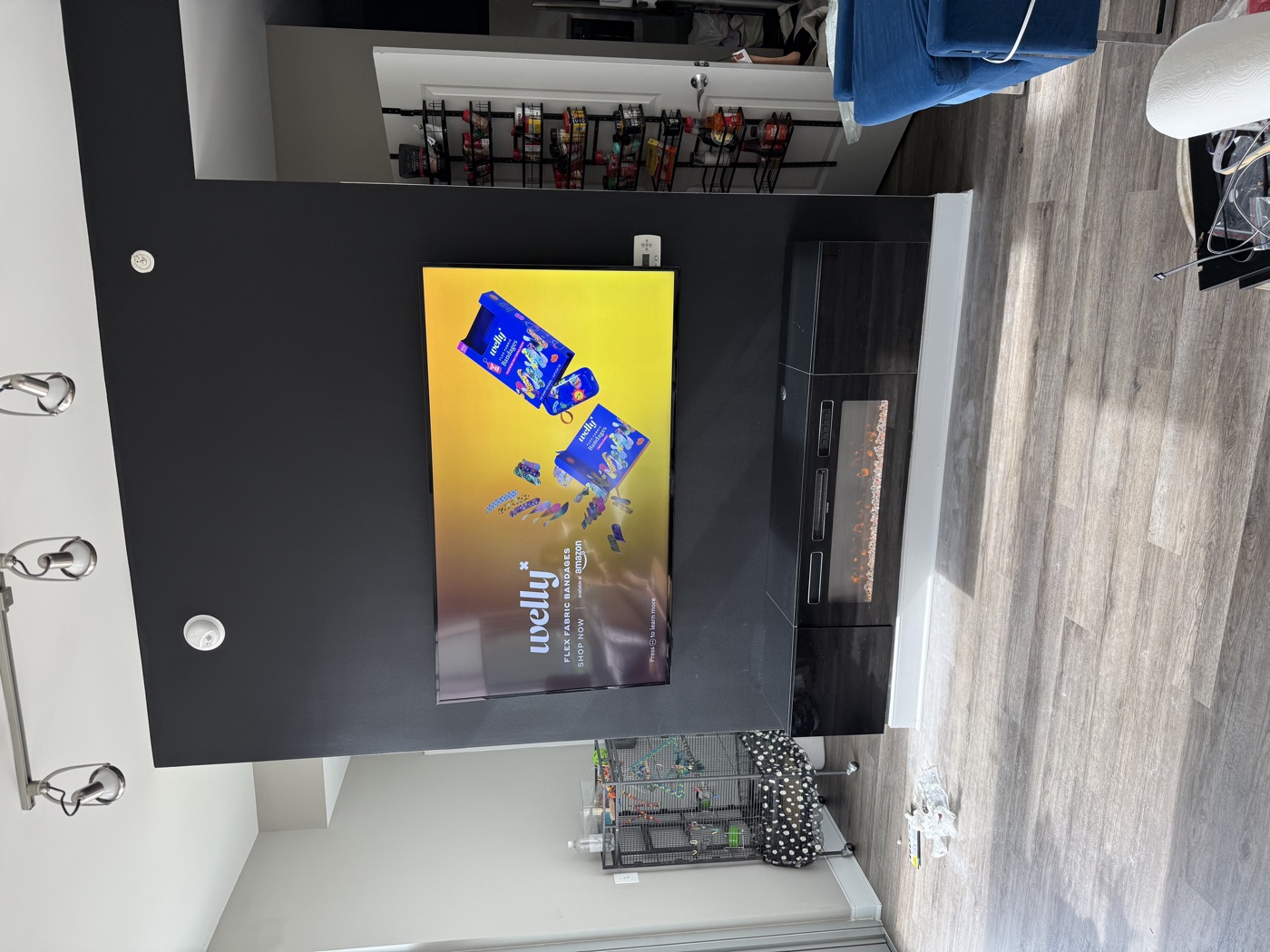 A TV mounted flush on a dark feature wall above a fireplace, no wires showing